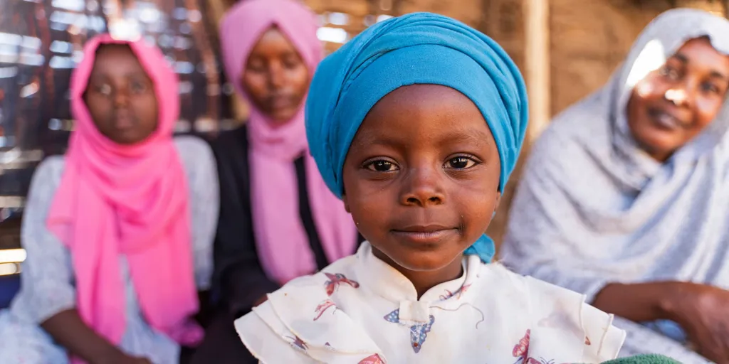 Sudanese refugee Diana Adam Rajab looks at the camera with her mother and sisters in the background at the Arkoum refugee camp in eastern Chad