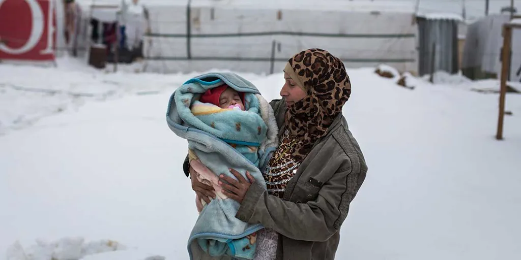 4 month old baby Yousef is held by his mother, Fatima in Dilhamye tented settlement in Bekaa Valley, Lebanon