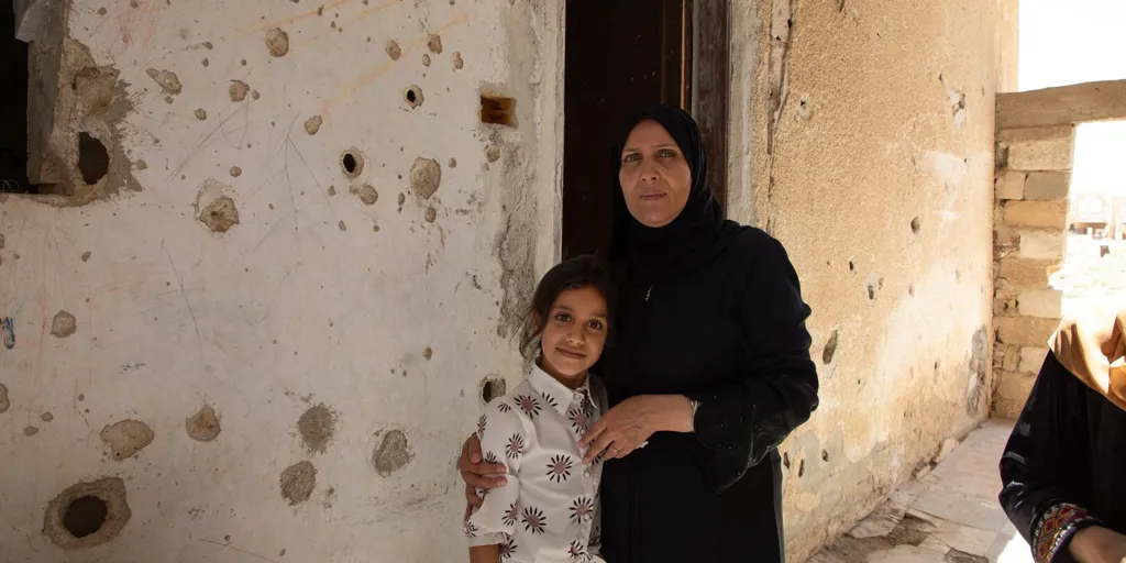 Basmah, 54, stands with her daughter Islam in front of the living room of their damaged house in Al Mansheya in Dar’a Governorate, upon returning back home.